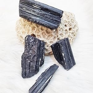 Raw Black Tourmaline stones resting on decorative mineral background