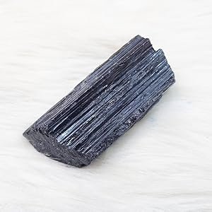 Single close up detailed view of unrefined black tourmaline rough stone crystal